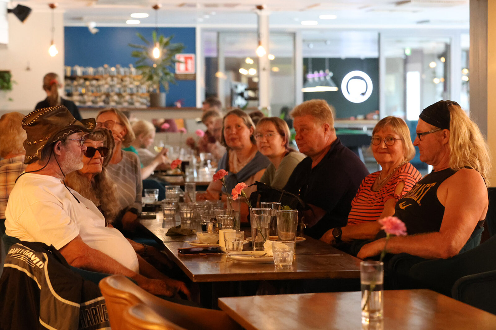 Iloinen seurue istuu pitkän pöydän ääressä ruokailemassa Ravintola Wallesmannissa